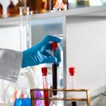 Scientist with gloves holding test tube in a modern lab setting.